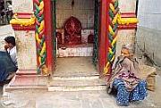 一名尼泊爾老婆婆坐在街邊的神龕前，這樣的神龕在加德滿都隨處可見。